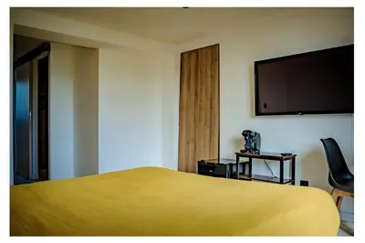 a hotel room with a yellow bed and a flat screen tv at La Bella Vista in Villelaure