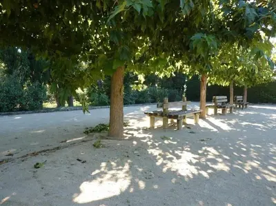 a row of benches sitting under trees in a park at Mazet provençal in Eyguières