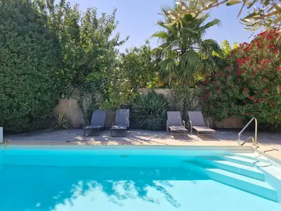 a swimming pool with two chairs and a palm tree at La Villa Jasmin - RENDEZ-VOUS EN PROVENCE in Monteux