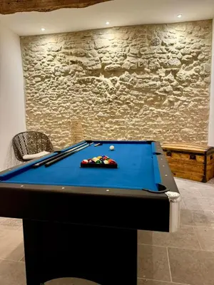 a blue pool table in a room with a stone wall at Mas Les Fabrys au coeur du Luberon in Bonnieux