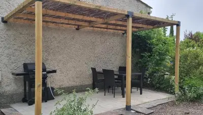 a wooden pergola with a table and a grill at La Passiflore in Mazan