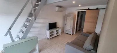 a living room with a staircase and a couch and a television at La Passiflore in Mazan