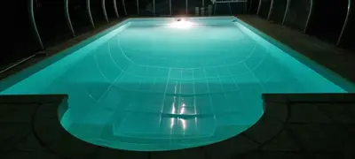 a swimming pool at night with a light on it at La Passiflore in Mazan