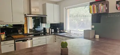 a kitchen with white cabinets and a sink and a window at La Maison du Soleil in Saint-Didier