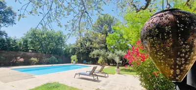 a swimming pool in a yard with two chairs and flowers at La Maison du Soleil in Saint-Didier