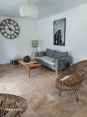 a living room with a couch and a clock on the wall at La Maison de Papé et Mamé in LʼIsle-sur-la-Sorgue