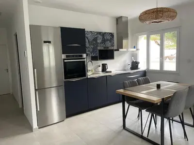 a kitchen with a table and a stainless steel refrigerator at La maison des Lilas in Aix-en-Provence
