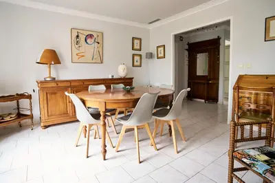 a dining room with a wooden table and white chairs at Maison familiale avec jacuzzi, quartier calme in Avignon