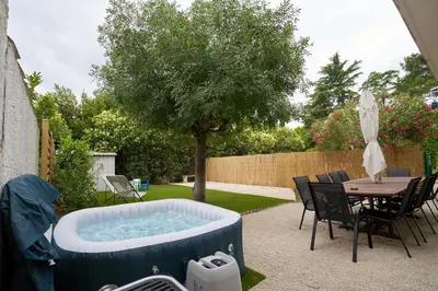 a hot tub in a yard with a table and chairs at Maison familiale avec jacuzzi, quartier calme in Avignon