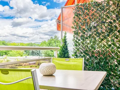 a table and chairs on a balcony with a green wall at Apartment Chez Lucie by Interhome in Aix-en-Provence