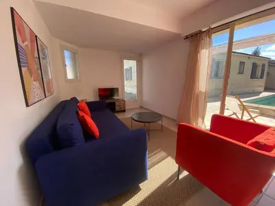 a living room with a blue couch and two red chairs at La maison en couleurs 3 étoiles, du calme à 10 minutes d'Avignon in Vedène