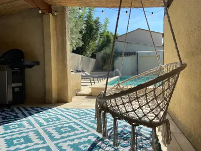 a hammock hanging from a porch with a pool at La maison en couleurs 3 étoiles, du calme à 10 minutes d'Avignon in Vedène