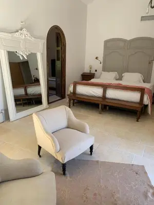 a bedroom with a bed and a chair and a mirror at Côté Ansouis in Ansouis