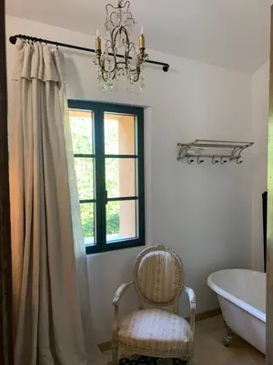 a bathroom with a chandelier and a chair and a tub at Côté Ansouis in Ansouis