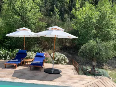 two chairs and an umbrella on a deck next to a pool at Côté Ansouis in Ansouis