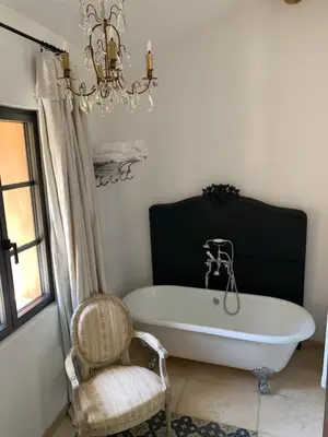 a bath tub in a bathroom with a chair and a chandelier at Côté Ansouis in Ansouis