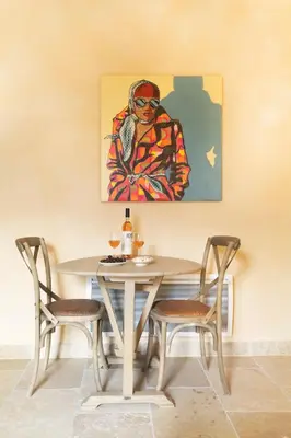 a table with two chairs and a painting on the wall at Domaine des Peyre in Robion en Luberon
