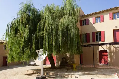 a weeping willow tree in front of a building at Domaine des Peyre in Robion en Luberon