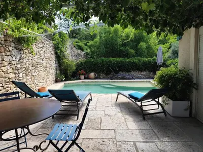 a patio with a table and chairs and a pool at Les trois gites in Robion en Luberon