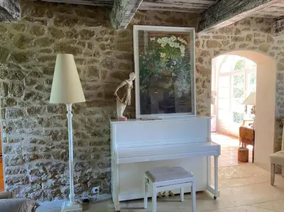 a white piano in a room with a stone wall at Le Mas Carradou , Mas de Prestige en campagne in Monteux