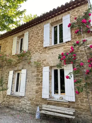 a brick building with white windows and pink roses at Le Mas Carradou , Mas de Prestige en campagne in Monteux