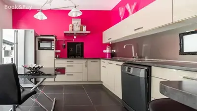 a kitchen with pink walls and white cabinets at Villa confortable à Morières-lès-Avignon avec jardin privé in Morières-lès-Avignon