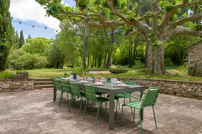 a table with green chairs sitting on a patio at Mas authentique à Eygalières in Eygalières