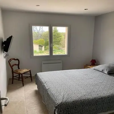 a bedroom with a bed and a chair and a window at Gîte l'olivier in Sainte-Tulle
