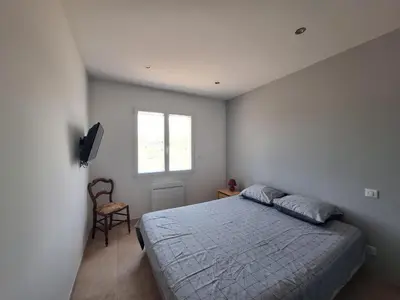a bedroom with a bed and a window and a chair at Gîte l'olivier in Sainte-Tulle