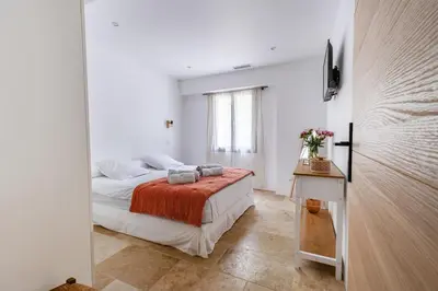 a white bedroom with a bed and a window at Gîte Le Figuier des Alpilles- 6p in Eygalières
