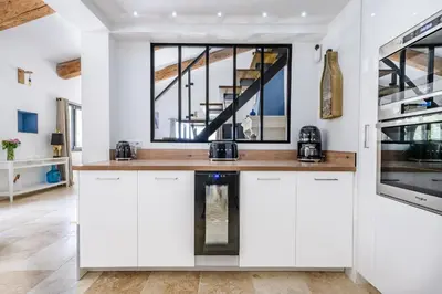 a kitchen with white cabinets and a large window at Gîte Le Figuier des Alpilles- 6p in Eygalières