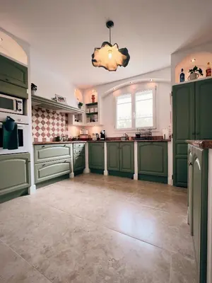 a large kitchen with green cabinets and a chandelier at Oustau di Gaffo in LʼIsle-sur-la-Sorgue