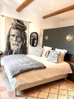a bedroom with a large bed with a painting of a man at Le Mas d'Emilienne in Coudoux
