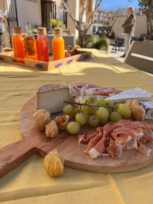 a wooden cutting board with meat and grapes and cheese at Le Mas d'Emilienne in Coudoux