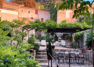 a table and chairs in a garden with plants at La Cigalou - Bonnieux Centre in Bonnieux