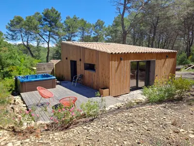 a small wooden house with two chairs on a deck at La Pinède de Venelles Jacuzzi privatif in Venelles