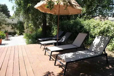 four lounge chairs and an umbrella on a patio at Charming Provencal Mas with pool by Taillades, close to Cavaillon in the Luberon, sleeps 6. in Les Taillades