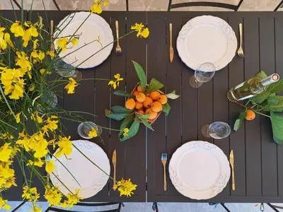 a table with plates and yellow flowers on it at Mas Les Figuières in Monteux