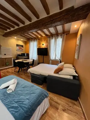 a hotel room with two beds and a table at Logement studio avec vue sur le centre Historique in LʼIsle-sur-la-Sorgue