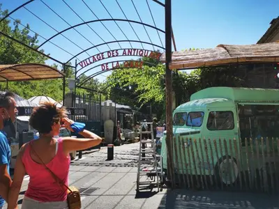 a woman taking a picture of a green truck at Logement studio avec vue sur le centre Historique in LʼIsle-sur-la-Sorgue