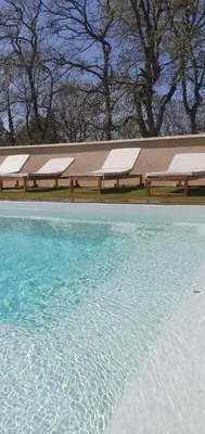 a wooden table with chairs next to a pool at La Villa Sable en Provence in Saint-Saturnin-les-Apt
