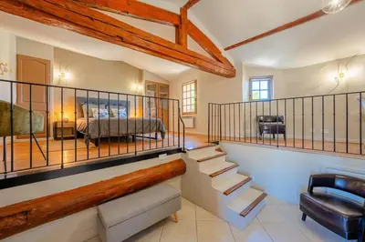 a bedroom with a bed and a staircase in a room at Ancien Moulin avec piscine proche Isle-sur-Sorgue in Le Thor