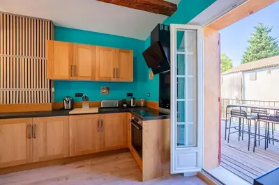 a kitchen with wooden cabinets and a balcony at Ancien Moulin avec piscine proche Isle-sur-Sorgue in Le Thor
