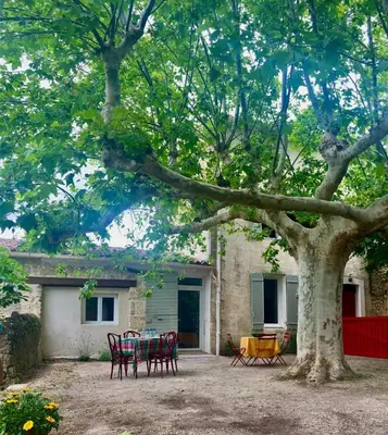 a table and chairs under a tree in front of a house at Bastide de la Couloubre in Mallemort