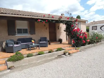 a house with a wooden deck with flowers on it at Villa au calme in Eyguières
