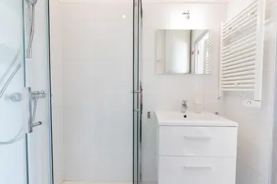 a white bathroom with a sink and a shower at Le Partage des eaux - 4 couchages - Hypercentre - Clim - Wifi in LʼIsle-sur-la-Sorgue