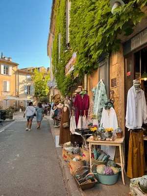 a group of people walking down a street next to a store at Maison de charme provençale en pierre in Puyvert