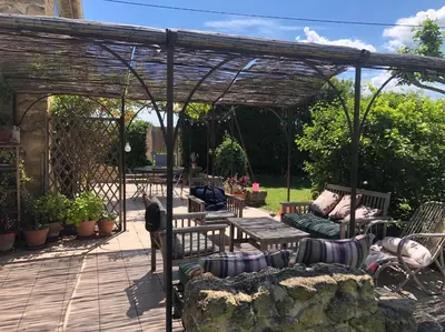 a wooden pergola with a bench and a table at Maison de charme provençale en pierre in Puyvert
