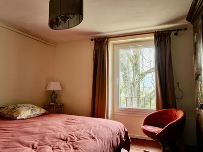 a bedroom with a bed and a window and a chair at L' Escale in Bonnieux