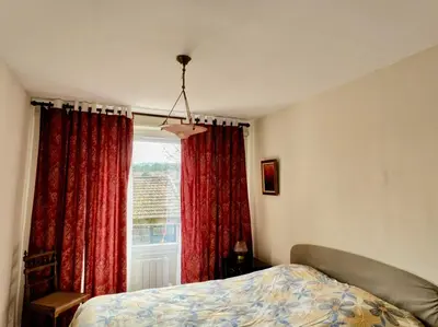 a bedroom with a bed and a window with red curtains at L' Escale in Bonnieux